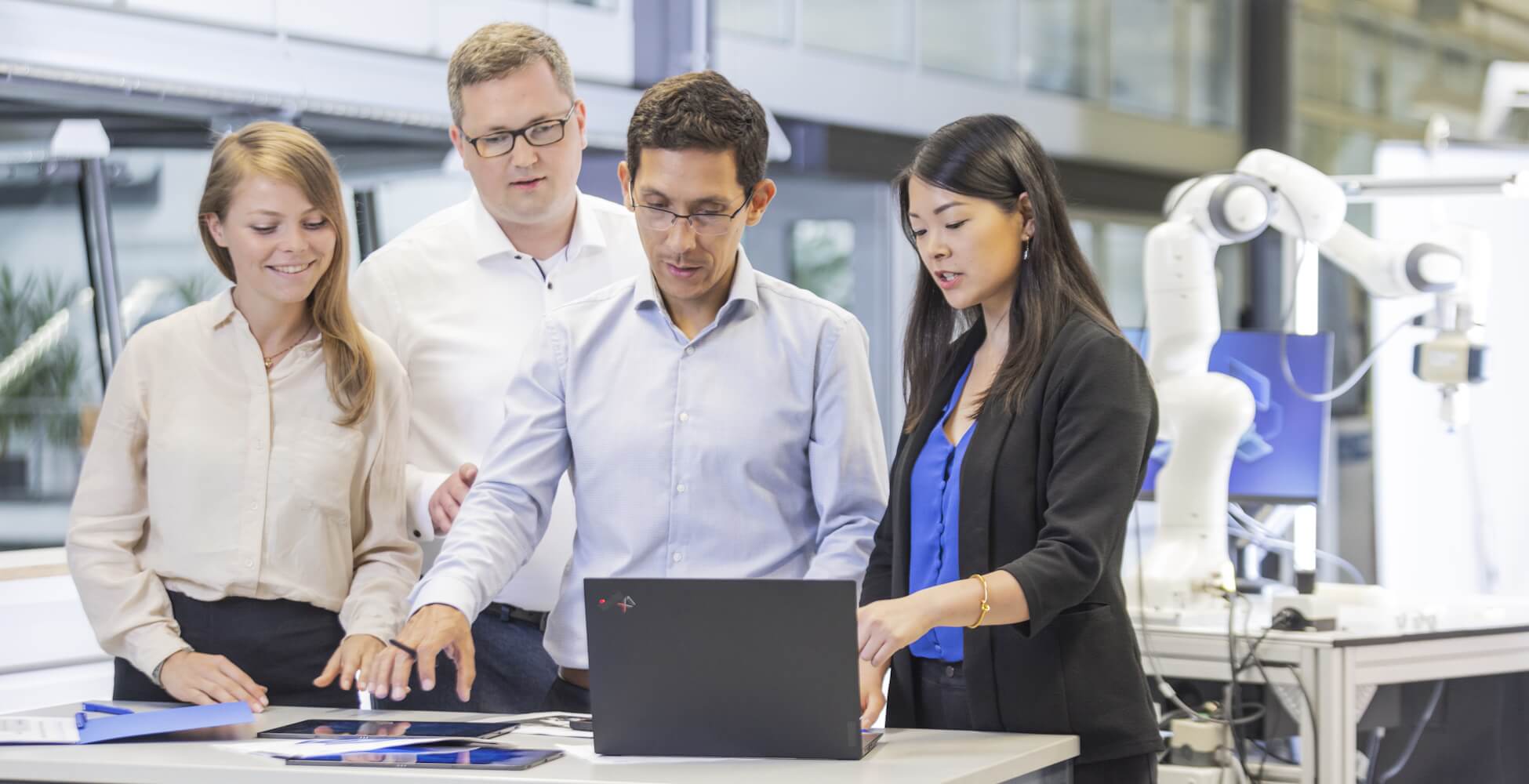 Gruppe von Personen steht um einen Laptop und bespricht sich